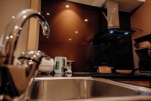 A modern kitchen with stainless steel appliances, a built-in oven, and a range hood. - Beachfront Luxury 2 Bedroom Apartment by Villuxy (Da Nang)