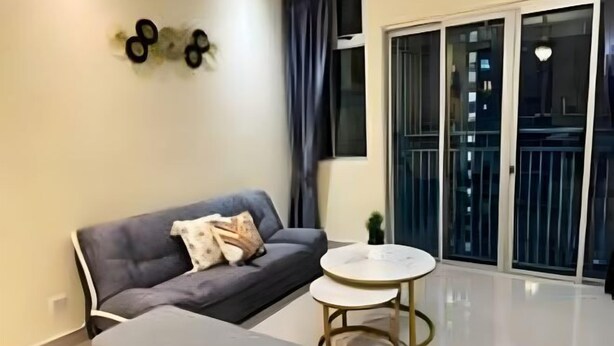 A modern living room with a grey sofa, a small round table, and a large window with a view of the city. - Meridin Bayvue (Plentong)