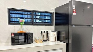 A modern kitchen with a microwave, toaster, and coffee maker on the counter, a refrigerator, and a window with blinds. - HH Villa Private Pool Bercham (Ipoh)