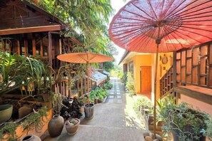 A narrow pathway flanked by potted plants and wooden structures, leading to a door at the end. - Baan Yung Hill Resort (Chiang Rai)
