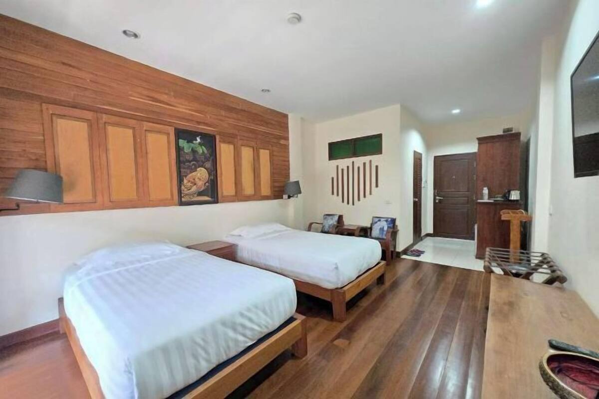 A room with two wooden beds, a wooden desk, a wardrobe, and a door.