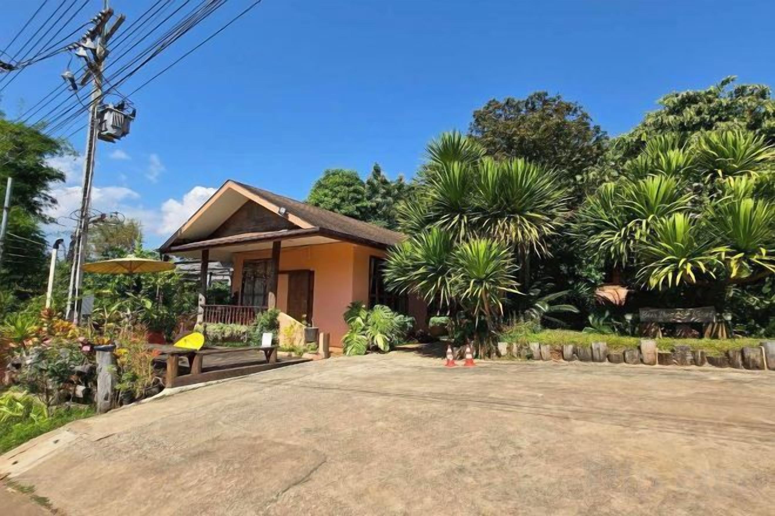 A single-story building with a porch, surrounded by tropical vegetation.