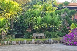 A garden with various tropical plants and a wooden sign. - Baan Yung Hill Resort (Chiang Rai)