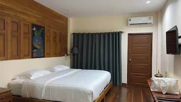 A bedroom with a wooden bed frame, a flat-screen TV mounted on the wall, and a door with a handle.