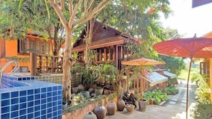 A tropical resort with a wooden building, tiled pool, and potted plants. - Baan Yung Hill Resort (Chiang Rai)