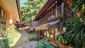 A courtyard with a wooden building, stone pathway, and lush greenery. - Baan Yung Hill Resort (Chiang Rai)