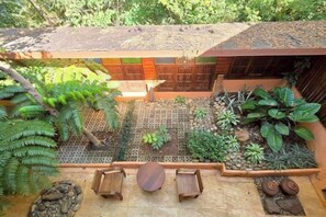 A courtyard with a thatched roof, a seating area with benches, and a variety of plants. - Baan Yung Hill Resort (Chiang Rai)