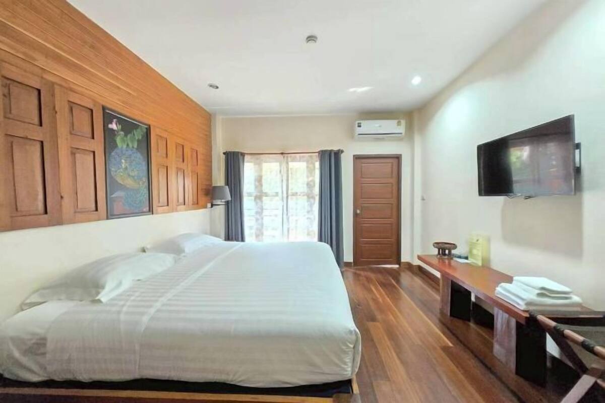 A hotel room with a bed, wooden paneling on the walls, a TV, and a desk with a chair.