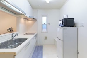 A compact kitchen with a sink, microwave, and refrigerator. - Etoile Soshigaya Okura by Tranova (Tokyo)