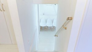 A staircase leading to a room with white walls, a white door, and a small table with chairs. - Etoile Soshigaya Okura by Tranova (Tokyo)