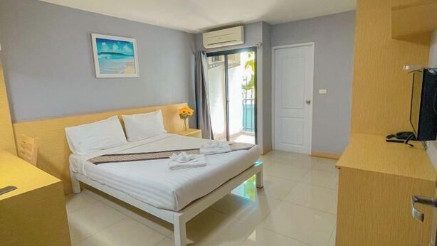 A hotel room with a bed, a desk, a chair, a TV, and a balcony with a view. - Big Zen Hotel (Nonthaburi)