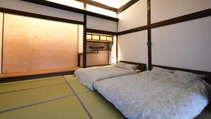 A traditional Japanese-style room with tatami flooring, two beds with patterned bedding, a sliding door with a view, and a small shelf with a lamp. - KandoStay Yatsugatake Fujiyama Terrace (Hokuto)
