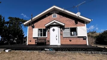A single-story house with a front porch, a central door, and a small window above the door.