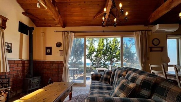 Una sala de estar acogedora con techo de madera, un sofá, una mesa y una chimenea.