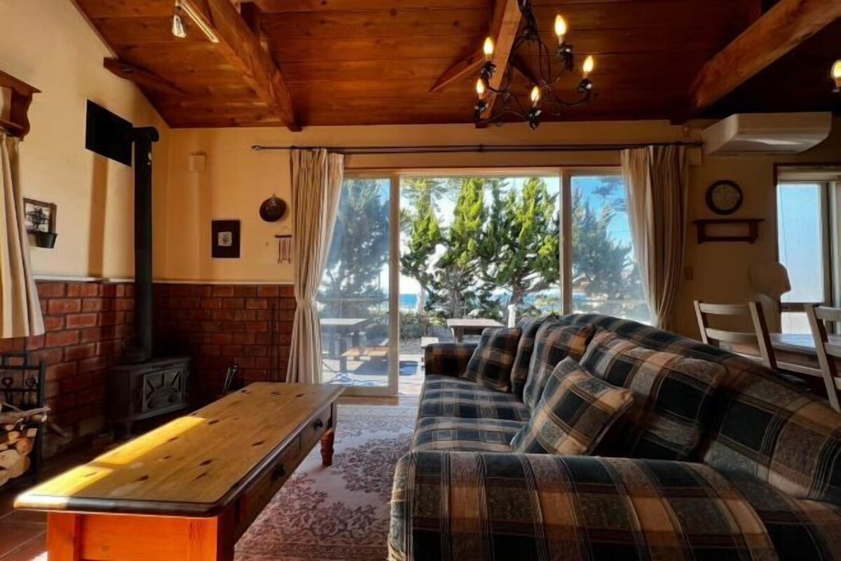 A cozy living room with a wooden ceiling, a sofa, a table, and a fireplace.