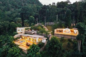A secluded resort with multiple buildings surrounded by dense forest, featuring a central circular structure and a large open area with a wooden deck. - PHULAYYA Chiangmai (Mae Taeng)