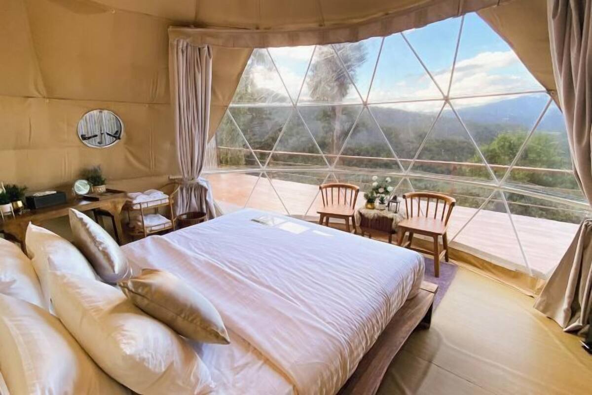 A spacious bedroom with a large bed, a small table, and two chairs.