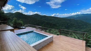 A wooden deck with a swimming pool and a view of a mountainous landscape.