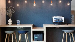 A reception desk with a computer monitor, a vase with white flowers, and two bar stools. - Holiday Inn Express & Suites MONHEIM AM RHEIN by IHG (Bedburg)