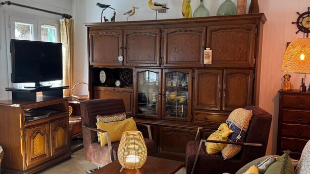 Een woonkamer met een televisie, houten meubels, een lamp en decoratieve objecten aan de muur.