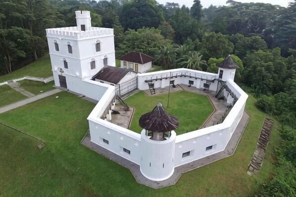 A white colonial-style building with a central courtyard, surrounded by lush greenery.