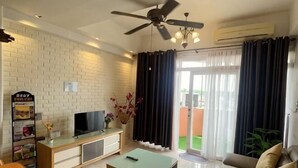 Un salon équipé d’un téléviseur, d’un canapé, d’une table basse et d’un ventilateur de plafond.