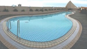 Une piscine avec un bord carrelé et un escalier en métal.