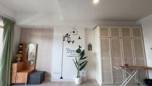 Une pièce comprenant un meuble en bois, un miroir, une plante en pot, un mur orné d’une citation décorative et une armoire.