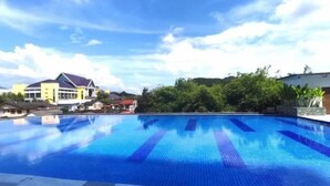 Ein Schwimmbecken mit klarem, blauem Wasser, umgeben von Grünflächen und Gebäuden.