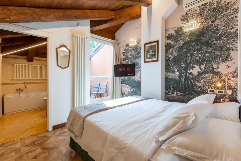 A bedroom with a bed, a wall-mounted TV, a mural, and a view of a bathroom.