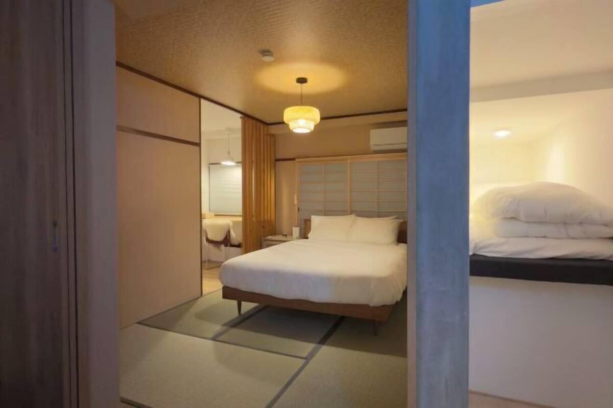 A hotel room with a bed, bedside table, and a window with curtains.