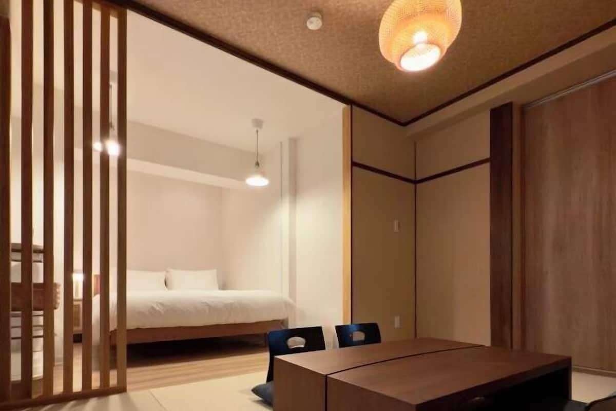 A modern bedroom with a bed, a wooden desk, and a chair.