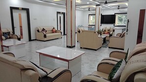 A modern waiting area with multiple sofas and armchairs, a flat-screen TV mounted on the wall, and a ceiling fan. - Hotel Gateway Asansol (Asansol)