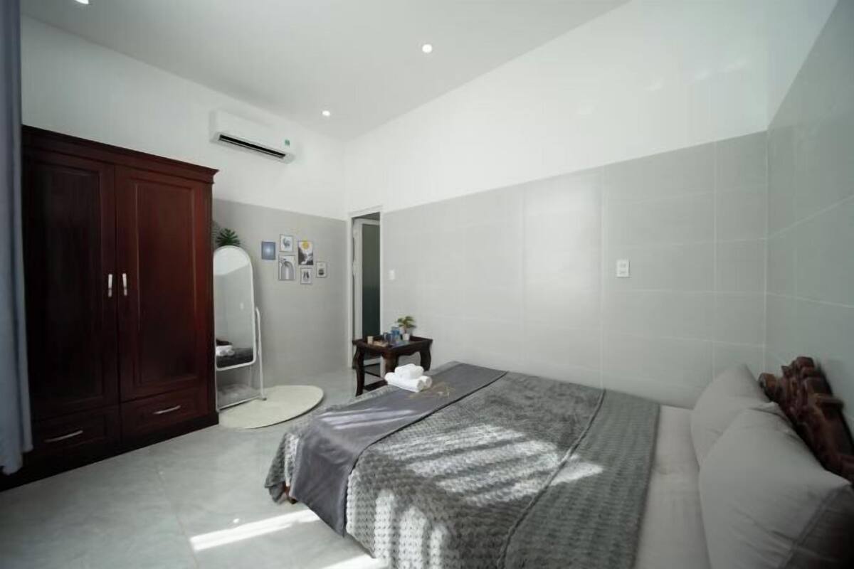 A bedroom with a bed, a wardrobe, a mirror, and a small table with a plant.