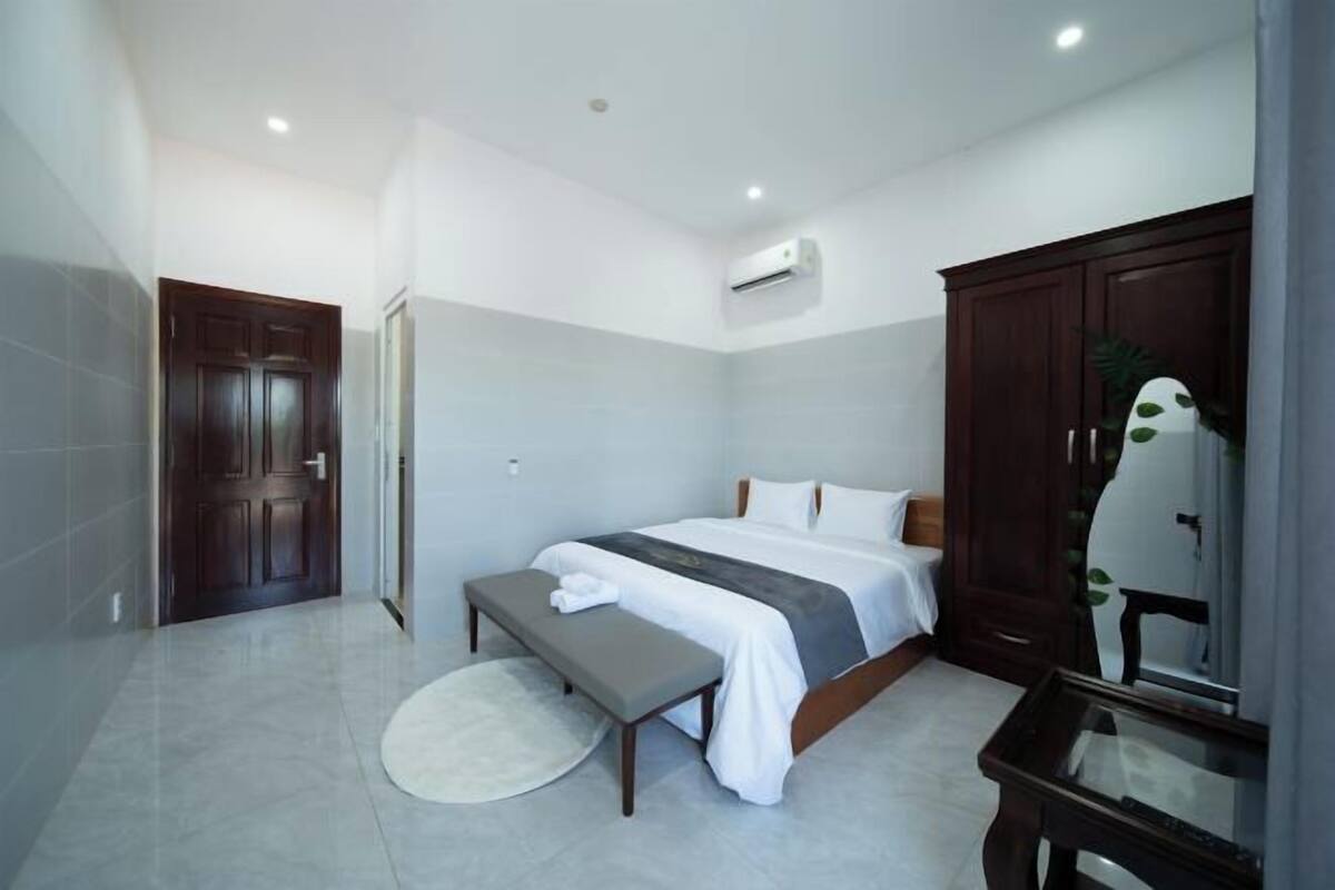 A bedroom with a bed, bench, and a mirror.