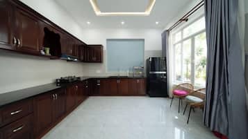 A modern kitchen with dark wooden cabinets, a black refrigerator, and a dining area with two chairs.