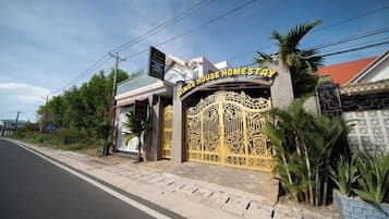 Una entrada con puerta protegida a una propiedad llamada 'King's House Homestay', con un portón decorativo y una placa.