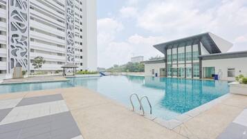 A swimming pool with a modern building and a tall structure in the background.
