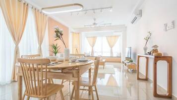 A modern dining area with a round table, chairs, and a small side table with a vase and a plant.