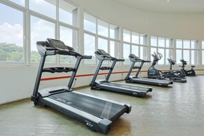A row of stationary bikes and treadmills in a room with large windows. - Vision Residence By Fei Hong (Puchong)