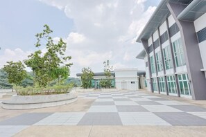 Un vaste espace extérieur doté d’un sol à carreaux, de bâtiments modernes et de verdure.