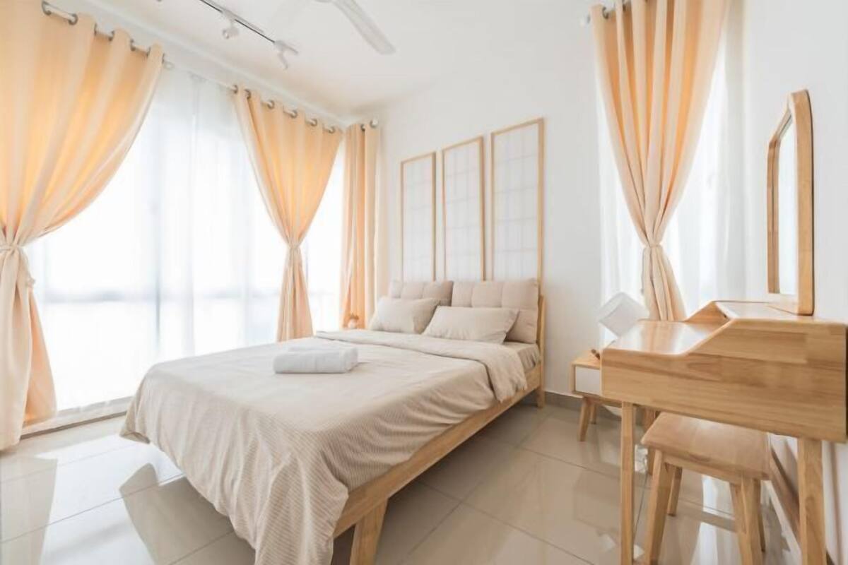 A bedroom with a bed, curtains, a desk, and a chair.