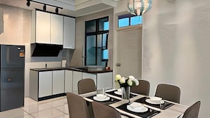 Una cocina moderna con armarios blancos, encimera negra y un comedor con mesa preparada para cuatro.