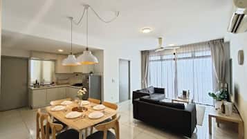 A modern living space with a dining area, sofa, and kitchen.