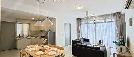 A modern living space with a dining area, sofa, and kitchen.