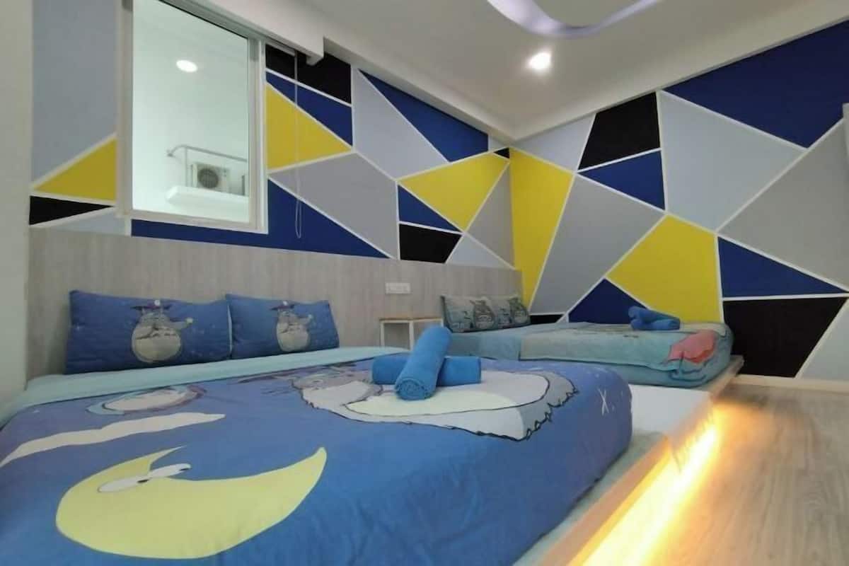 A bedroom with a geometric-patterned wall, a large window, and a bed with a blue and yellow design.