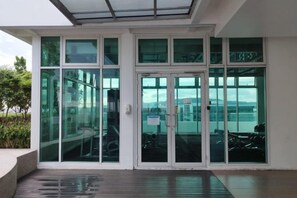 Entrada de un edificio moderno con puertas y ventanas de vidrio, un área techada y vista al cielo.