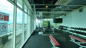 A gym with exercise equipment, benches, and a TV screen. - reStary Cartoon Themed Homestay (Kota Kinabalu)