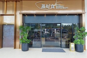 The entrance to a restaurant with a sign above the door, potted plants, and a reflection of a car in the glass. - reStary Cartoon Themed Homestay (Kota Kinabalu)