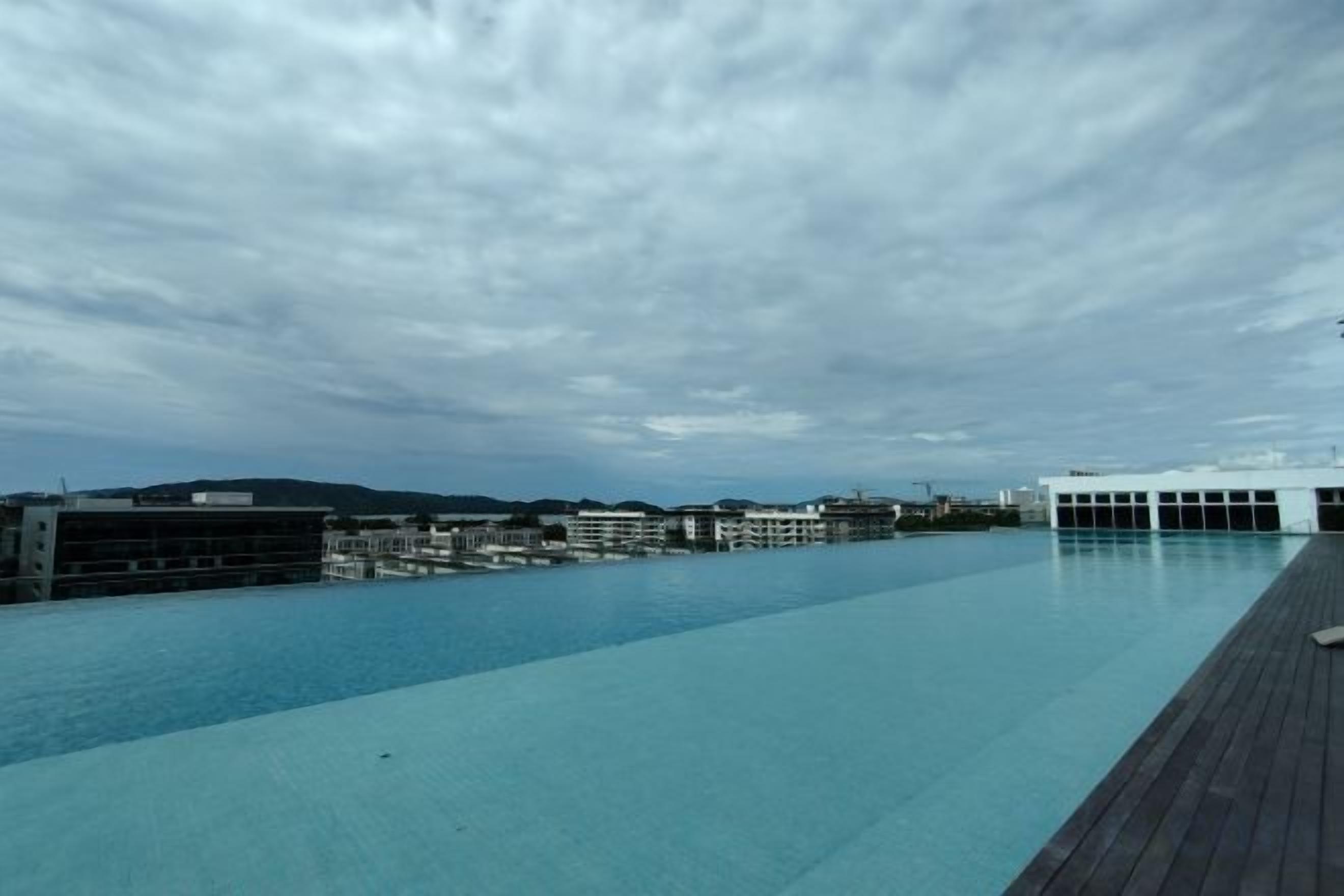 A swimming pool with a wooden deck, surrounded by buildings.